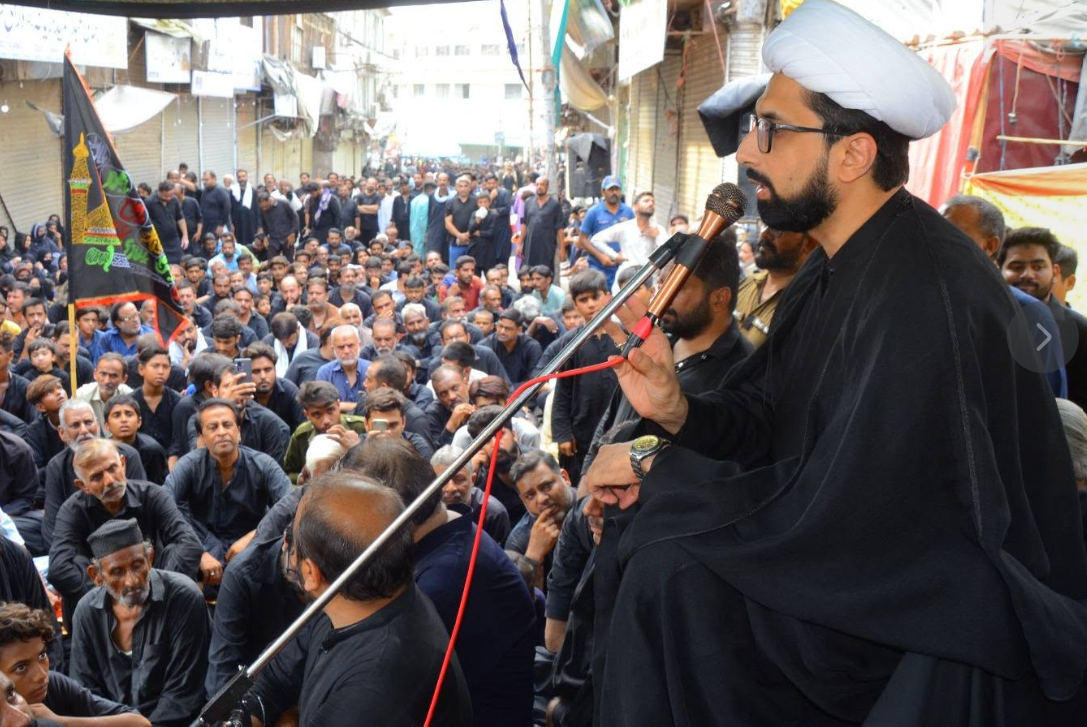 Maulana Taqi Mehdavi addressing a large Muharram gathering amid the standards of Karbala